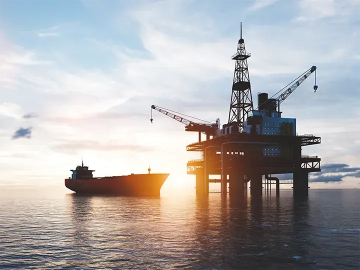 Oil and gas rig in the ocean with oil container ship in the background
