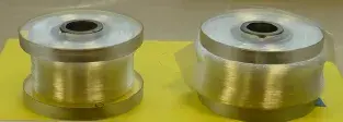 Photo of two 400m long coils, wound onto identical 15mm diameter spools. The coil on the left has 60μm fiber (with a 120μm coating) whilst the coil on the right has 80μm fiber (with a 165μm coating).